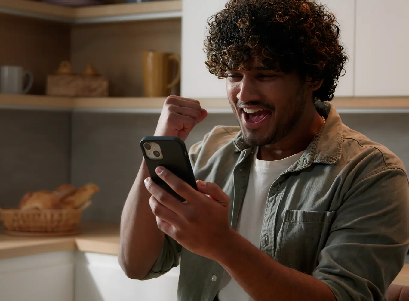 Man looking at his phone with a fist pump, celebrating a positive moment in his gambling recovery journey